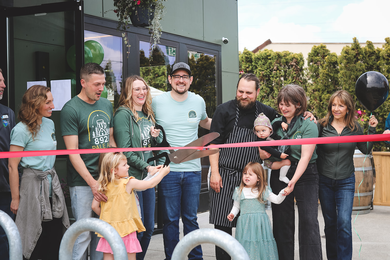 Image of a group of several families at a ribbon-cutting ceremony for the opening of their new business.